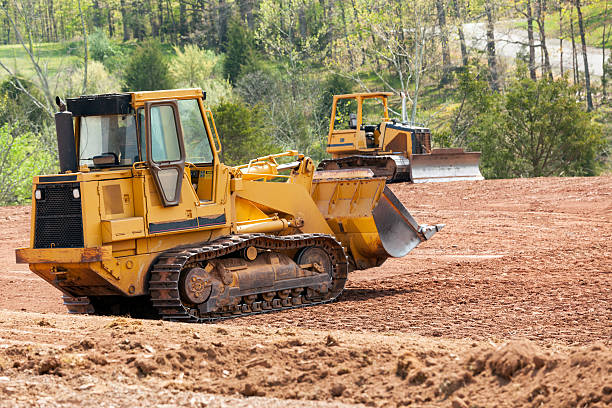 Large earth mover digger clearing land Land being levelled and cleared by yellow earth moving digger glade photos stock pictures, royalty-free photos & images
