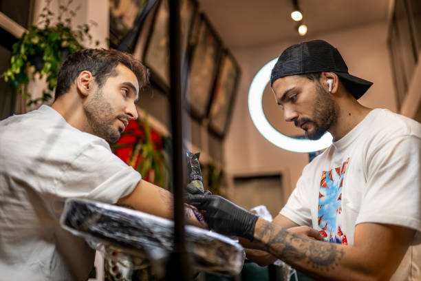 istock Young tattoo artist tattooing his customer in his studio 1778712428