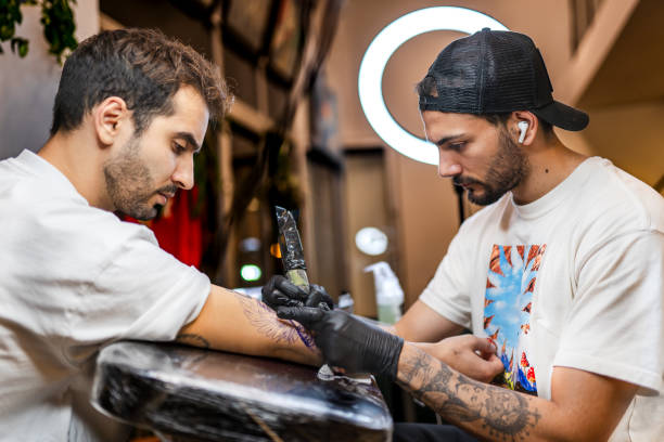 Young tattoo artist tattooing his customer in his studio
