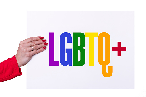 Woman hand holding a LBGBTQ+ white poster on white background. Studio shot.