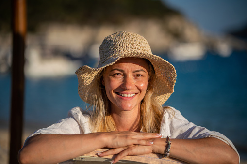 Portrait of a happy woman resting on the beach and looking at camera