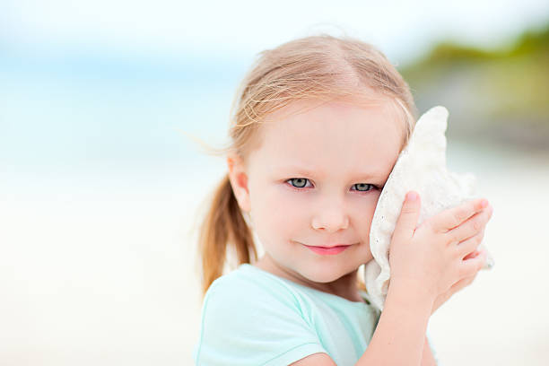 istock Little girl with a seashell 177876200