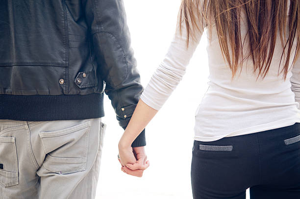 Back of Young couple holding hands stock photo