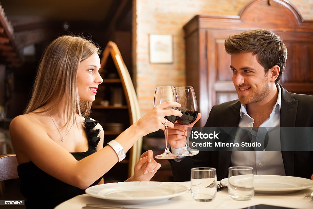 Elegant couple clinking wine glasses at a nice restaurant Couple toasting wineglasses in a luxury restaurant Adult Stock Photo