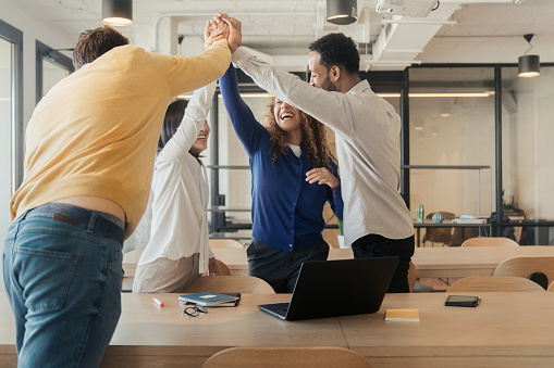 Laughing businesspeople celebrating a success by doing a high five at the office