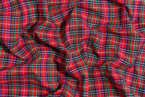 The texture of crumpled, wrinkled fabric in a cell of traditional Scottish tartan colors. Background for your mockup or design