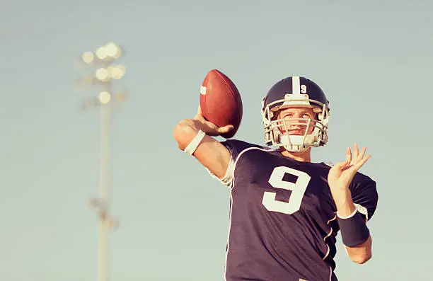 An American football Quarterback passes the ball downfield.