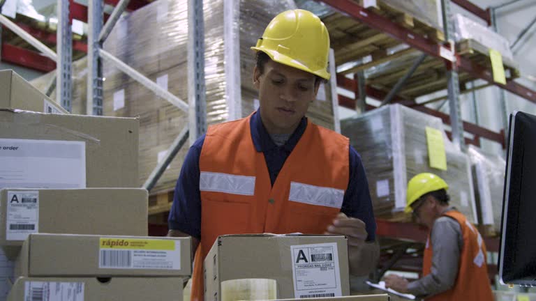 Male warehouse packer sealing boxes with tape inside storage facility