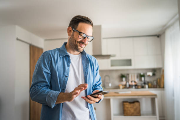istock adult man with eyeglasses stand at home use mobile phone sms texting 1778896520