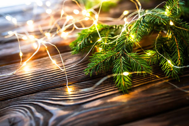 istock Border with green spruce branches with Christmas lights on a wooden background. Pine tree, Christmas evergreens. 1778897039
