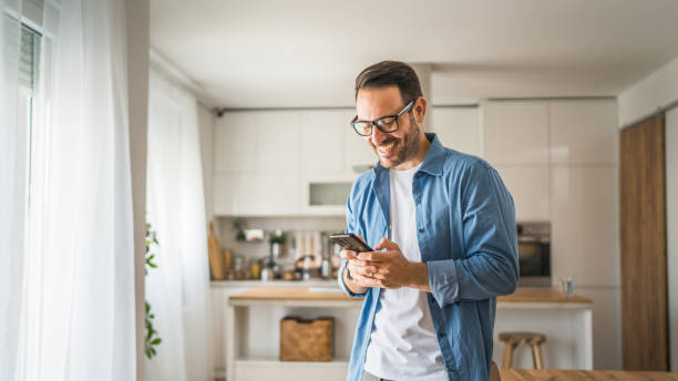 istock adult man with eyeglasses stand at home use mobile phone sms texting 1778897583