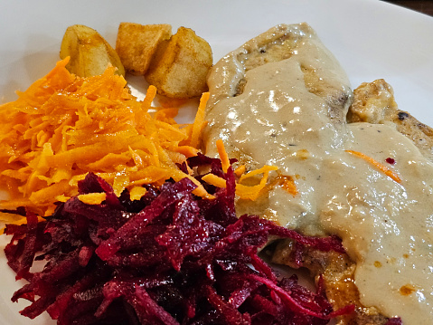 Chicken accompanied by French fries, grated carrot and beetroot