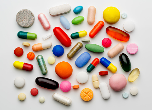 Health themes: Large group of assorted capsules and pills on white background
