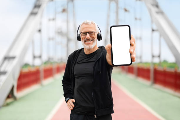 istock Cheerful elderly sportsman showing phone with white blank screen 1778925830