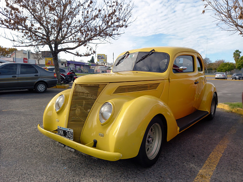 Buenos Aires, Argentina - Jun 4, 2023: Old yellow 1937 Ford V8 coupe 5 window street rod in a parking lot. Front view. Grille. Classic car show. Sunny day