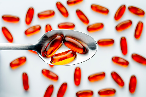 Heath Themes: Close up of fish oil vitamin gelatin capsules with Omega-3 into spoon