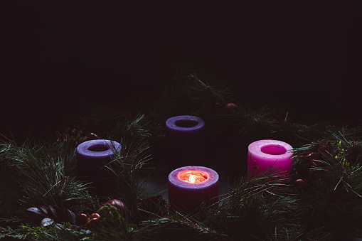 Rustic advent wreath in a dark room with one candles lit with copy space for the first week of advent