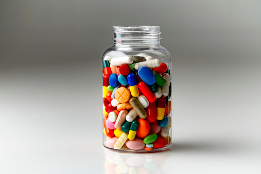 Health themes: Large group of assorted capsules and pills in transparent pill container