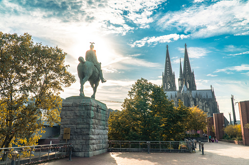 Cologne, Germany, September 11, 2023: View of Cologne Cathedral and the equestrian statue of Kaiser Wilhelm II against the background of the sun and cloudy sky