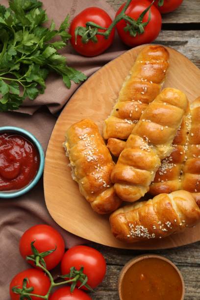 istock Delicious sausage rolls and ingredients on wooden table, flat lay 1779050314