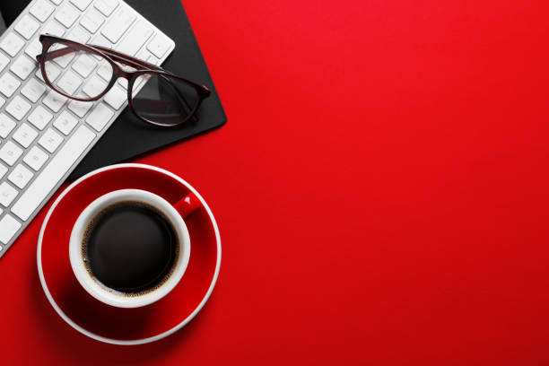 istock Cup with aromatic coffee, glasses and keyboard on red background, flat lay. Space for text 1779065284