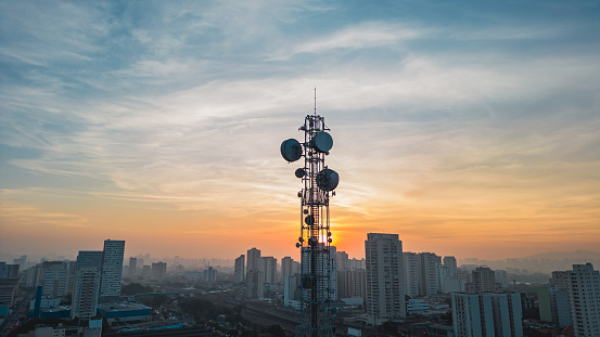 Communication antennas together and city in the background at sunset