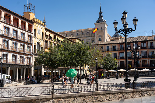 Plaza Zocodover with the Spanish flag waving and the Alcázar of Toledo in the background. Castilla la Mancha. Spain. July 29, 2023.