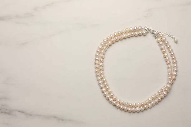 istock Beautiful pearl necklace on white marble table, top view. Space for text 1779180510