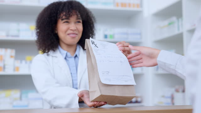 Friendly pharmacists giving prescribed medicine to a customer at a pharmacy. A woman healthcare professional handing a patient their medication at a dispensary. Medical provider passing client pills