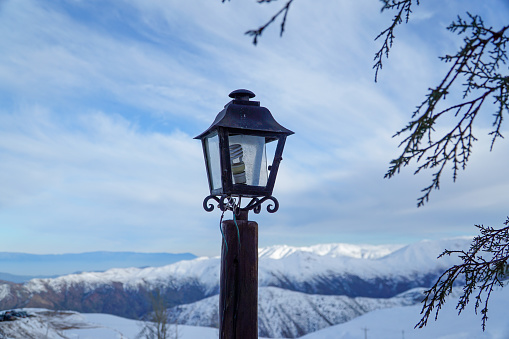 A lantern glows warmly on a mountain path in the rugged cordillera, guiding the way.