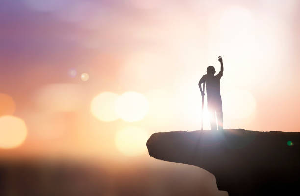 istock Silhouette a disabled man standing up and raising his crutches at  sunset background 1779194108