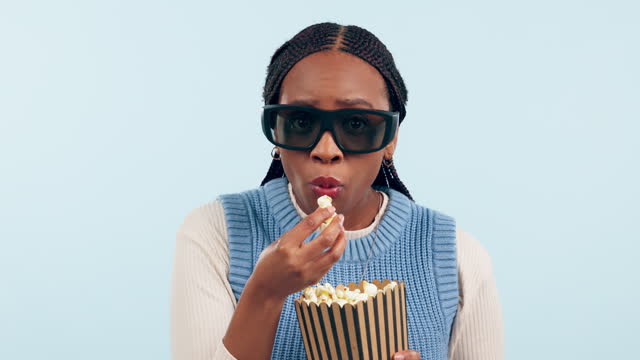 Woman, popcorn and 3d cinema in studio for movie, eating or fear with anxiety by blue background. Gen z African girl, food and snack with scared face, glasses or watching tv for streaming horror film