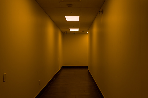 Empty hallway - dimly lit - orange glow - fluorescent light. Taken in Toronto, Canada.