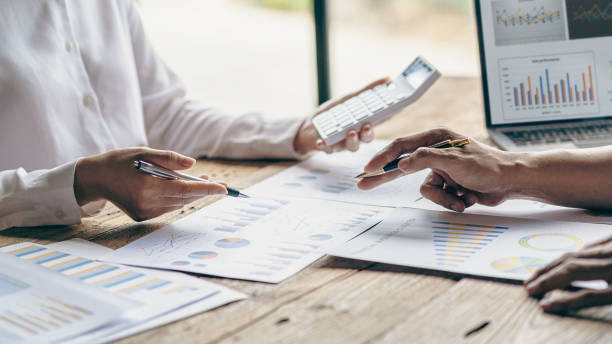 istock business team working They are analyzing financial reports and using calculators. accounting calculations And partners point to financial reports to analyze the company's sales plans. 1779227246