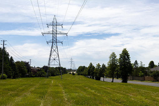 Power lines - green field - blue sky - suburban neighborhood. Taken in Toronto, Canada.