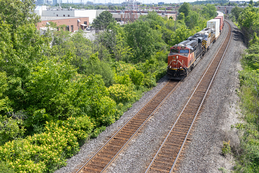 Canadian National Railway freight train on tracks - aerial view - trees and buildings in background. Taken in Toronto, Canada.