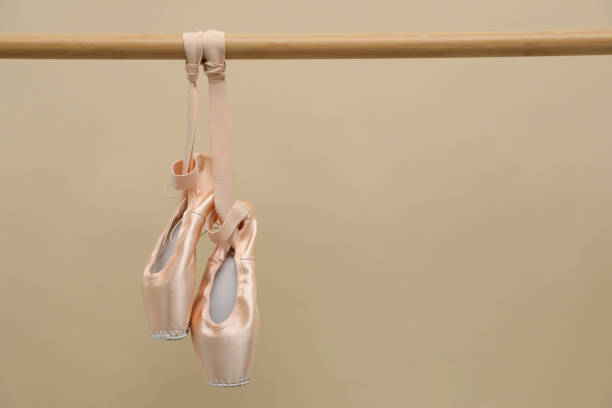 istock Elegant pointes hanging on ballet barre against beige background. Space for text 1779263832