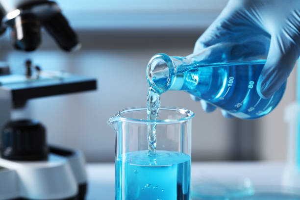 istock Scientist pouring light blue liquid from flask into beaker in laboratory, closeup 1779267169
