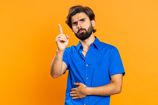Displeased upset middle eastern man reacting to unpleasant awful idea, dissatisfied with bad quality, wave hand, shake head No dismiss idea dont like proposal. Guy isolated on orange studio background