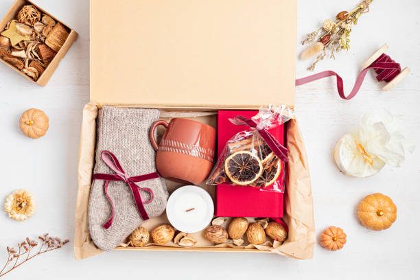 Preparing care package with warm socks, book, coffee cup, aroma spices. Personalized eco friendly basket for fall, winter holidays, christmas, wishig recovery to family, friend. Get well soon gift box