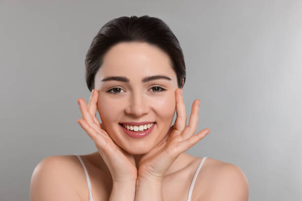 istock Young woman massaging her face on grey background 1779315905