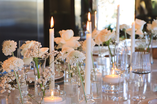 A holiday celebration table with modern decor of white and glass, silver background and natural light