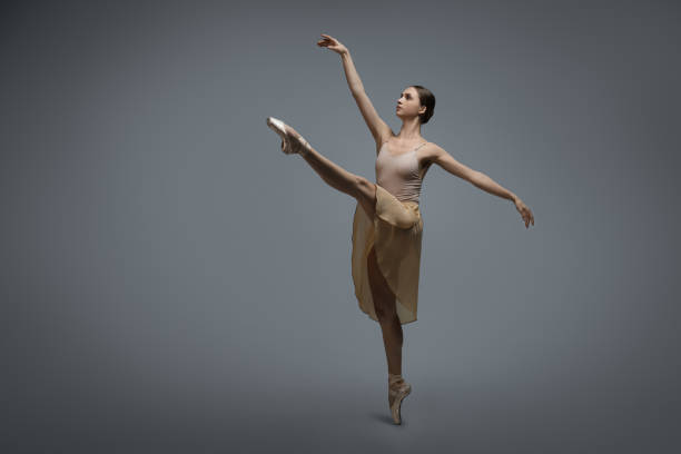 istock Young ballerina practicing dance moves on grey background. Space for text 1779328755