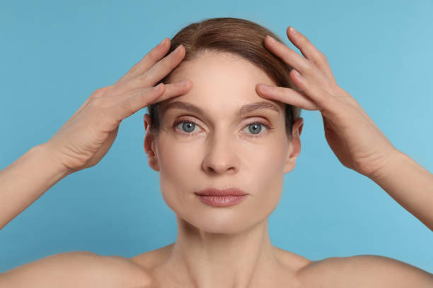 istock Woman massaging her face on turquoise background 1779331438