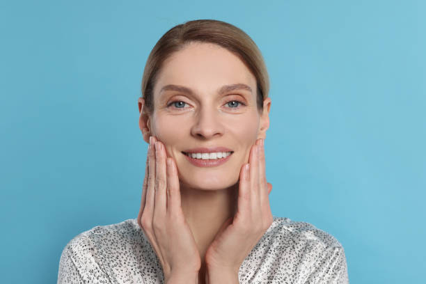 istock Woman massaging her face on turquoise background 1779332492