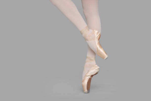 closeup of ballerina feet on pointe in pointe shoes with black background