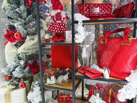 Sremska Mitrovica, Serbia, December 17, 2021. Shop window with beautiful things and gifts for the New Year and Christmas. Showcase decoration in red and white colors. Dwarf, bags, wallets, fir branch