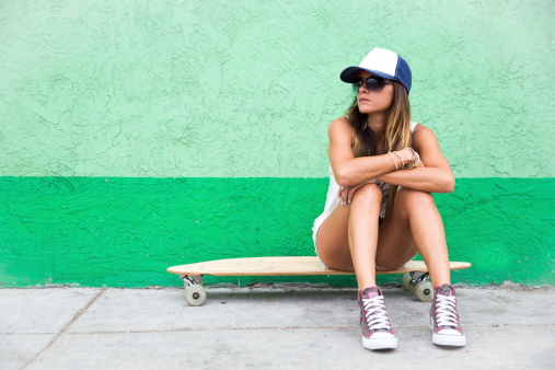 Unhappy teen girl sitting on her skateboard.