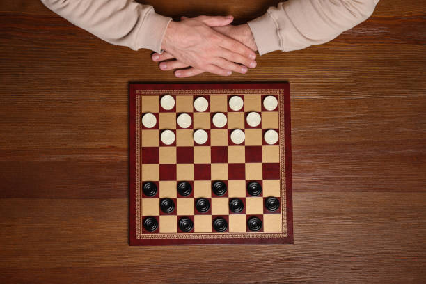 istock Playing checkers. Man thinking about next move at wooden table, top view 1779370518