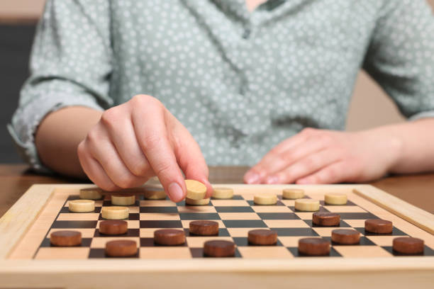 istock Playing checkers. Woman thinking about next move at wooden table, closeup 1779371584